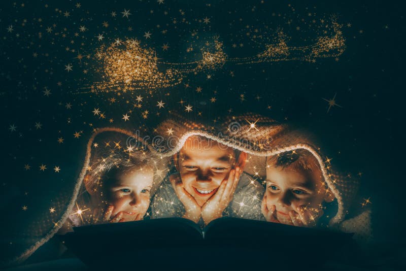 Children Reading a Book Under a Blanket with Light Stock Photo Image