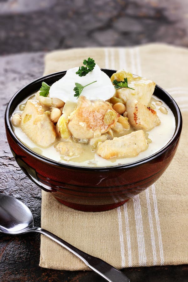 A delicious bowl of white chicken chili topped with sour cream and parsley. Shallow depth of field. A delicious bowl of white chicken chili topped with sour cream and parsley. Shallow depth of field.