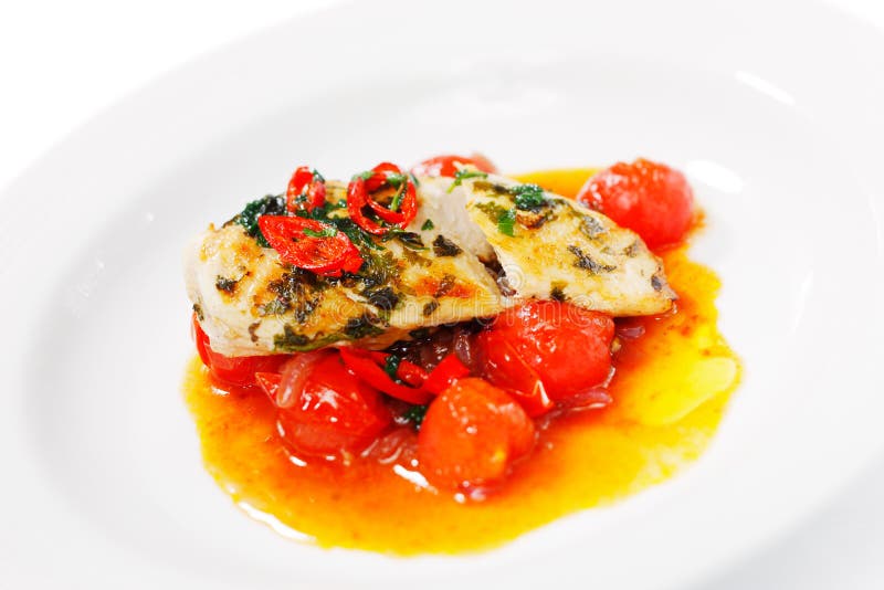 Chili chicken on a bed of roasted cherry tomatoes royalty free stock photo
