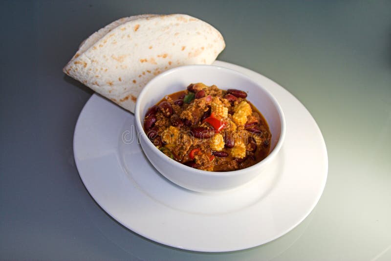 White porcelain bowl with chili con carne, plate, tortilla