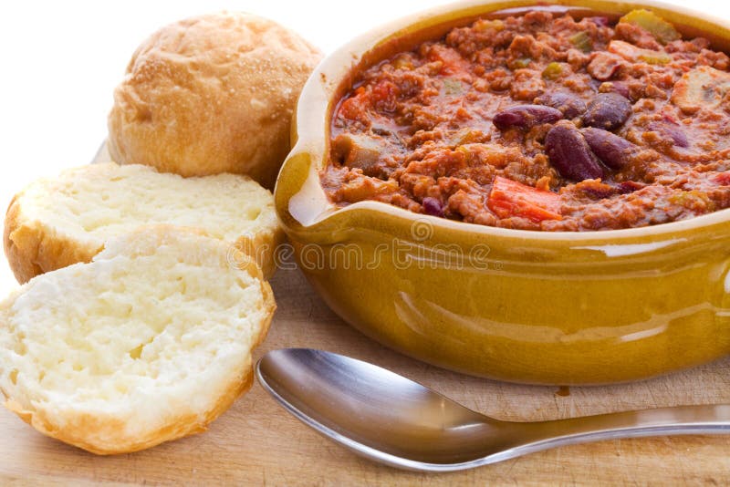 Bowl of chili con carne with crusty buns and spoon