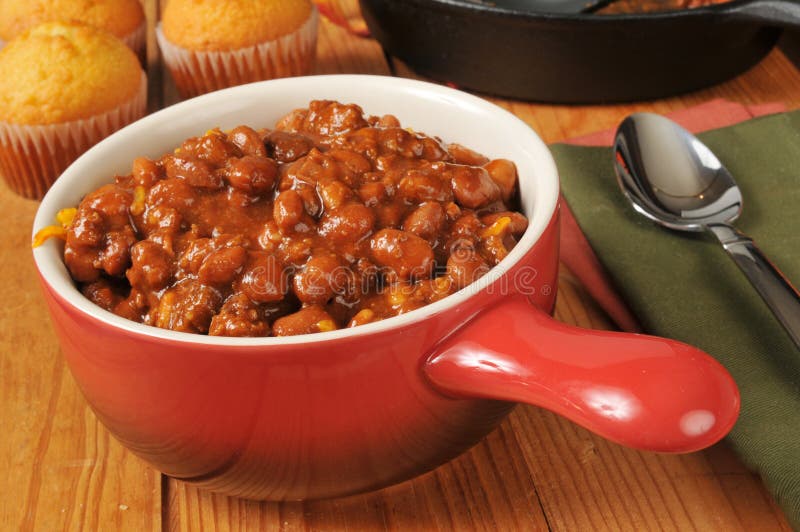 A bowl of chili con carne with cornbread muffins