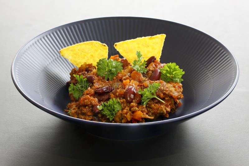 Chili con carne meal in a rustic bowl. Traditional dish of mexican cuisine with kidney beans, minced meat, parsley and tortilla ch stock photography Chili con carne meal in a rustic bowl. Traditional dish of mexican cuisine with kidney beans, minced meat, parsley and tortilla ch stock photography