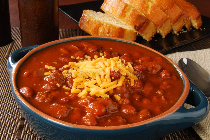 A crock of chili with shredded cheese and cornbread. A crock of chili with shredded cheese and cornbread