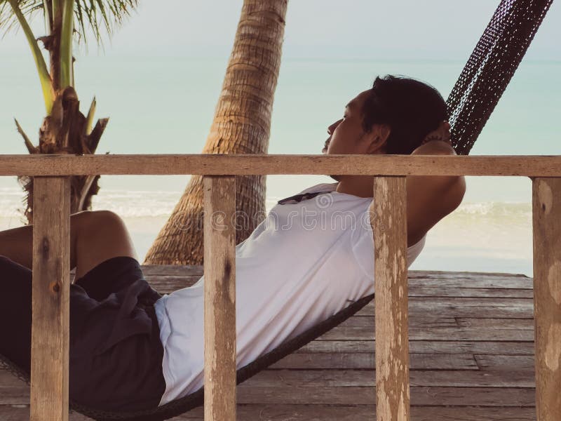 Chilling beach vibe of man sleeping on hammock in the hut by the beach royalty free stock photos