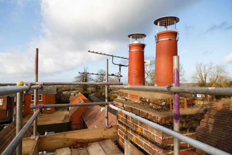 Chimney pots and scaffolding during construction work, UK. Repairing chimney pots with scaffolding on a roof. Construction work on a house renovation, UK stock image Chimney pots and scaffolding during construction work, UK. Repairing chimney pots with scaffolding on a roof. Construction work on a house renovation, UK stock image