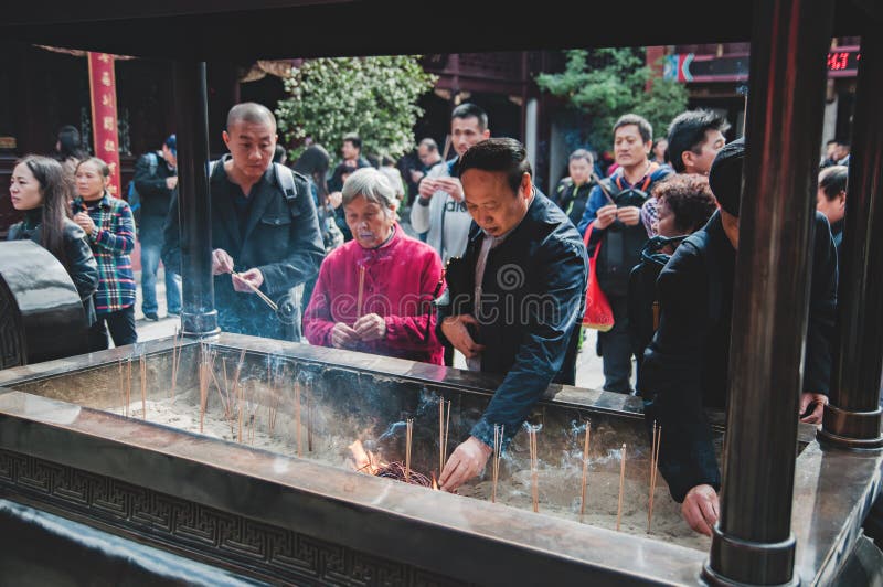 CHINA, SHANGHAI - 7 DE NOVEMBRO DE 2017: Os povos asiáticos estão rezando em um templo budista e em umas varas ardentes do incens imagem de stock CHINA, SHANGHAI - 7 DE NOVEMBRO DE 2017: Os povos asiáticos estão rezando em um templo budista e em umas varas ardentes do incens imagem de stock
