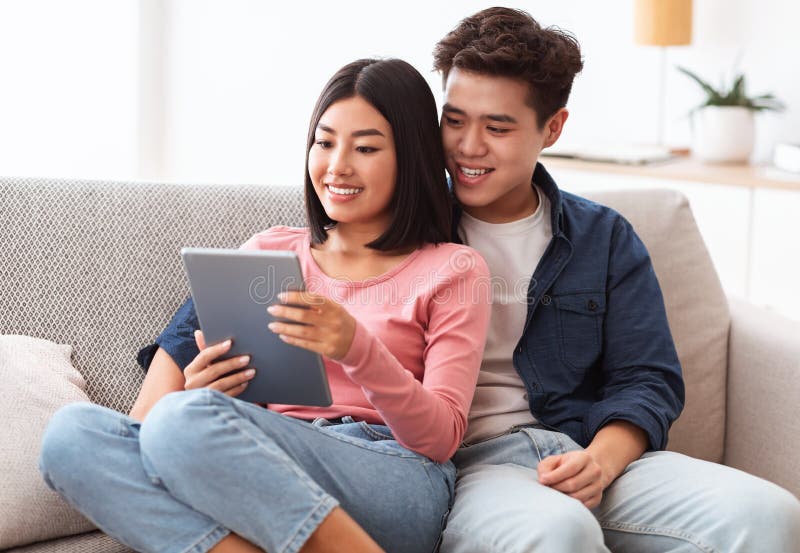Relaxed Japanese Couple Chilling Together at Home, Using Gadgets