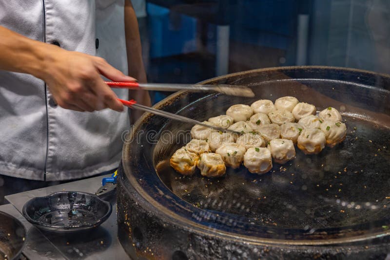 Chinese Chef Cooking Fried Dumplings on Hot Pan in Kitchen Stock Image