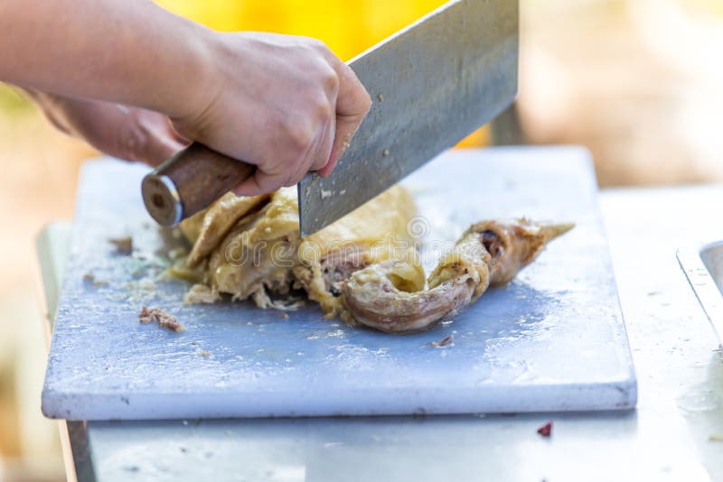 A Chinese Chef Hand Using a Knife and Chopping Chicken Meat into Small Pieces Stock Photo