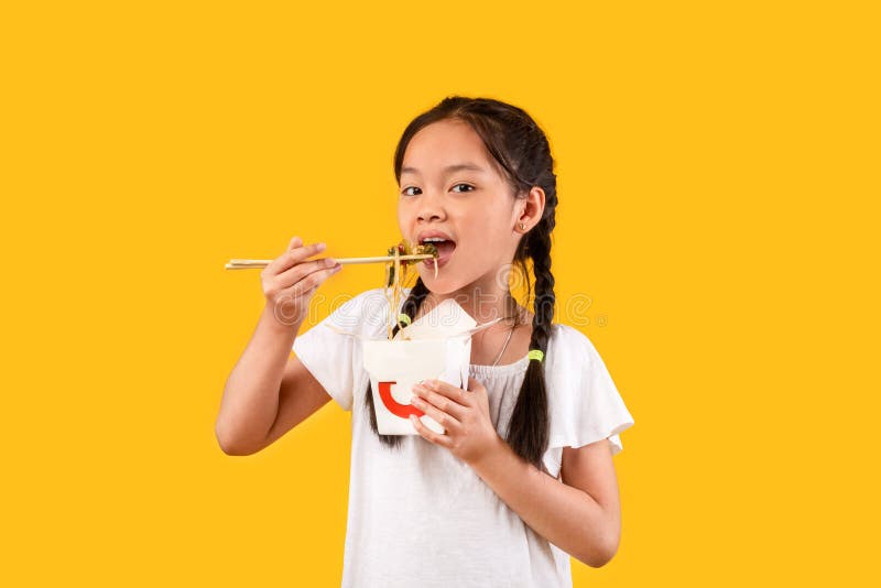 Chinese Girl Eating Noodles With Chopsticks Holding Box, Yellow Background