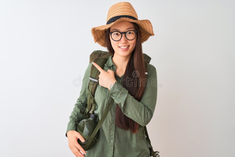 Chinese hiker woman wearing canteen hat glasses backpack over  white background cheerful with a smile of face pointing