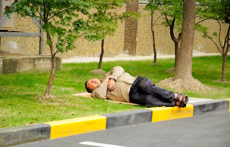 A chinese man laying down sleeping on a board in the shade in Shanghai China. A chinese man laying down sleeping on a board in the shade in Shanghai China.