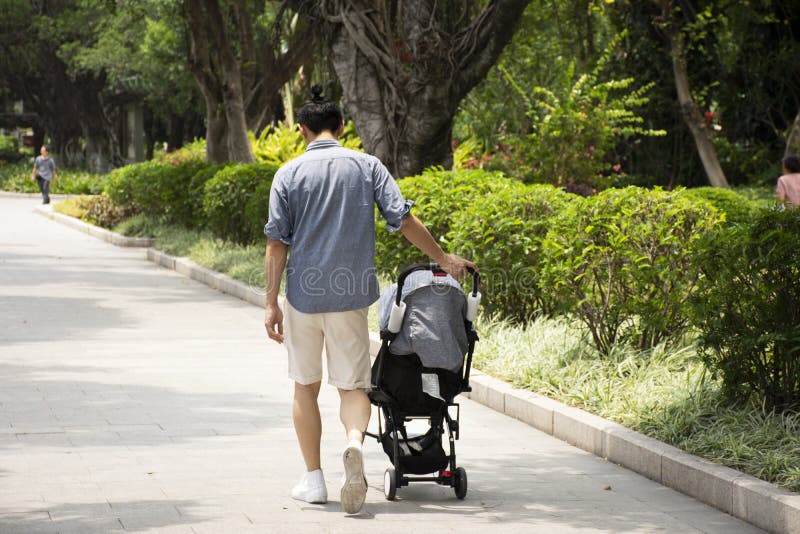 Chinese mensenmensen kar duwen en baby die op de weg in tuin bij openbaar park in de stad van Shantou of Swatow-in Guangdong, Chi stock afbeeldingen Chinese mensenmensen kar duwen en baby die op de weg in tuin bij openbaar park in de stad van Shantou of Swatow-in Guangdong, Chi stock afbeeldingen