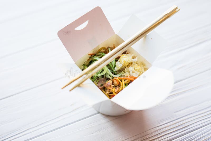 Chinese noodles in takeaway box on wooden background. Food.