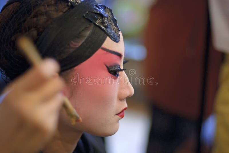 A chinese opera actress is painting her face