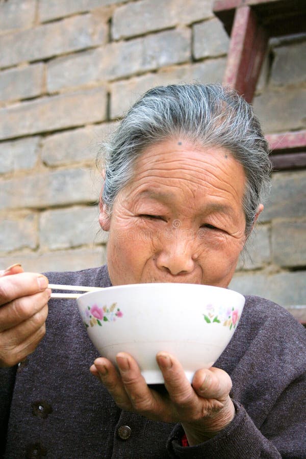 Chinese oude vrouw met eetstokjes en kom