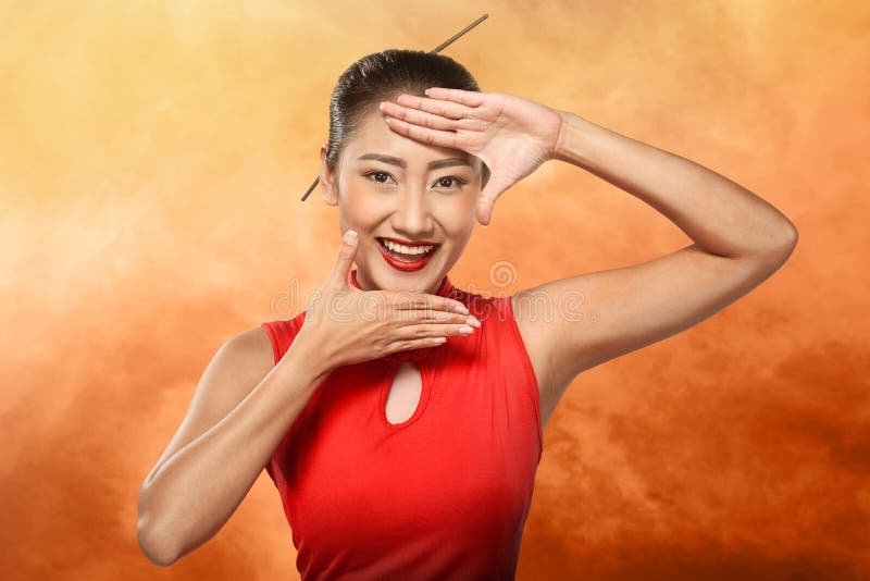 Chinese woman in cheongsam dress framing her face with hand