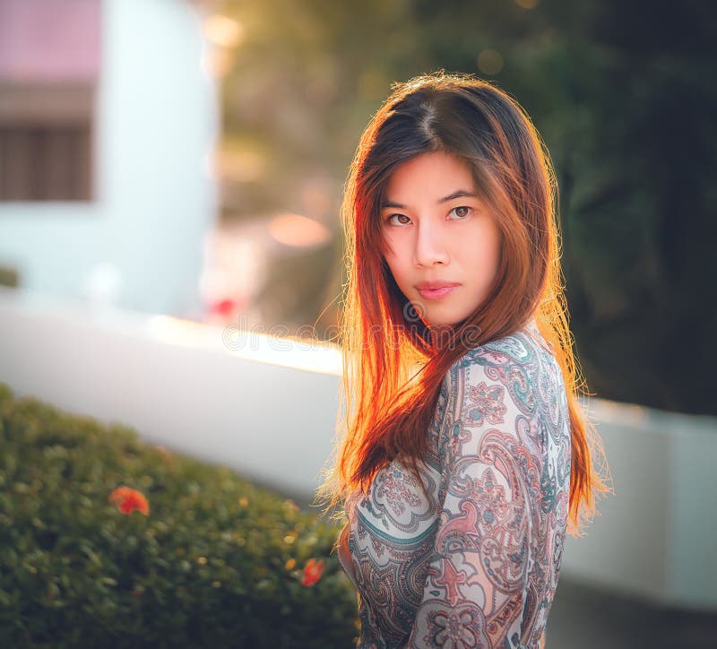 Chinese Woman With Tanned Beauty Skin Portrait In A Green Garden With Sun Light For Beauty And