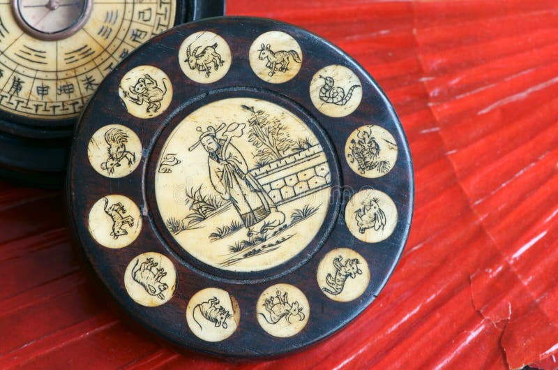 Starožitný Čínský Zvěrokruh Kolo s feng shui kompas vyroben z ryté kosti a dřeva na červeném pozadí ventilátor.