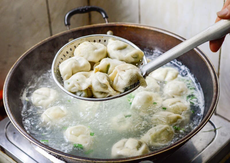 Chinesische Familie, die gekochte Mehlklöße im Wok kocht stockfotos