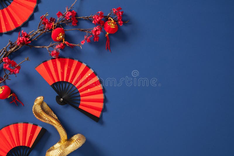 Chinesisches Neujahrskonzept mit lebendigen roten Fans goldene Schlangen-Figuren und blühenden Zweigen auf einem stockfotos