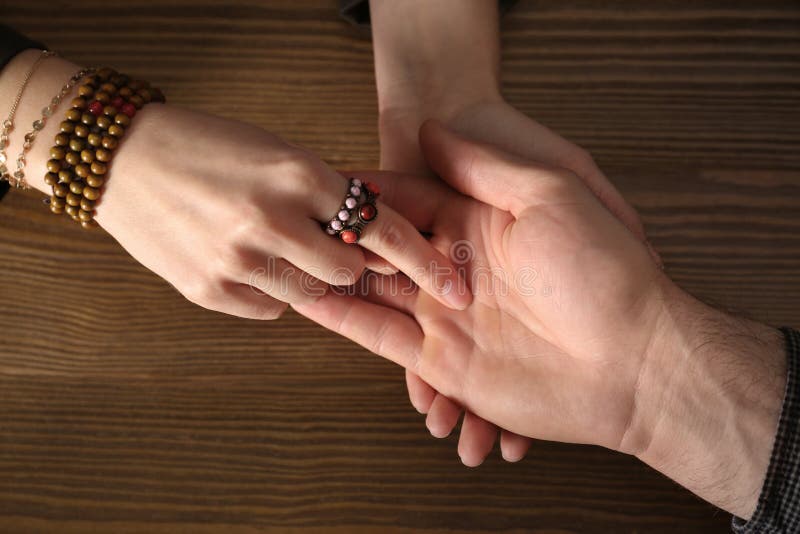 Chiromancer reading lines on man`s palm at table stock photo Chiromancer reading lines on man`s palm at table stock photo