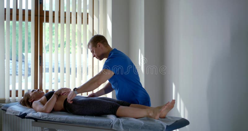 Chiropractor sta ispezionando una paziente negli uffici delle cliniche per la diagnosi fotografia stock