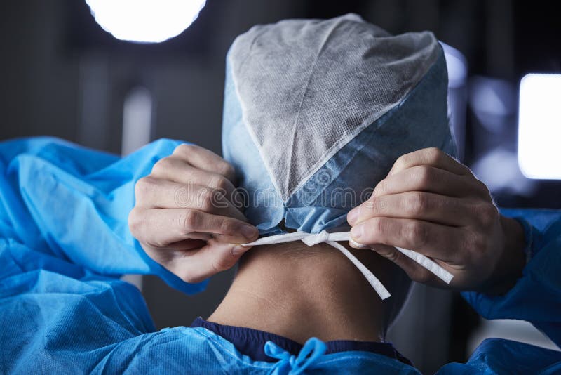 Chirurg, der chirurgische Kappe in der Vorbereitung, hintere Ansicht bindet