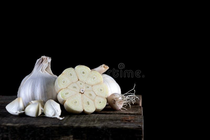 Chiuda su aglio su legno, isolato nero indietro frantumato immagini stock libere da diritti Chiuda su aglio su legno, isolato nero indietro frantumato immagini stock libere da diritti