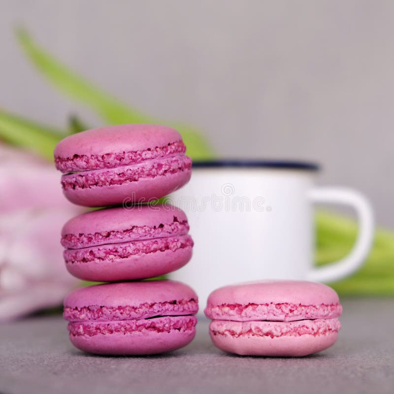 Chiuda su dei macarons francesi dolci, tazza di tè o caffè e fiori della molla su fondo grigio fotografia stock libera da diritti Chiuda su dei macarons francesi dolci, tazza di tè o caffè e fiori della molla su fondo grigio fotografia stock libera da diritti