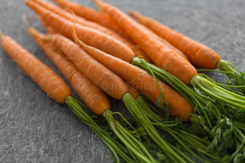 Healthy eating, food, dieting and vegetarian concept - close up of carrot bunch on table. Healthy eating, food, dieting and vegetarian concept - close up of carrot bunch on table