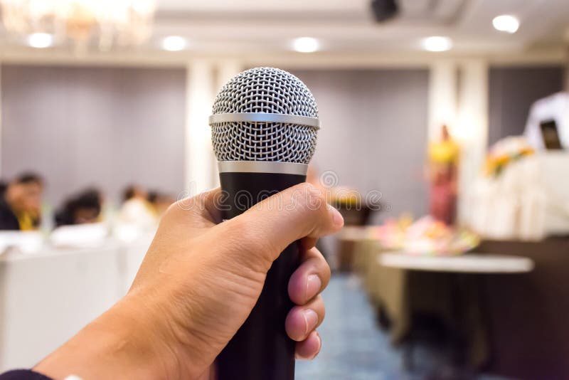 Chiuda su del microfono della tenuta della mano del ` s dell'uomo nella sala per conferenze fotografie stock libere da diritti Chiuda su del microfono della tenuta della mano del ` s dell'uomo nella sala per conferenze fotografie stock libere da diritti