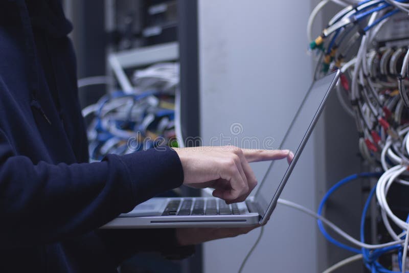 Chiuda su del tecnico delle mani che lavora al computer portatile nel centro dati Annuncio fotografia stock