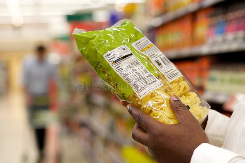 Chiuda su dell'etichetta dell'alimento della lettura della donna di colore in supermercato