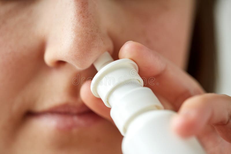 Healthcare, flu, rhinitis, medicine and people concept - close up of sick woman using nasal spray. Healthcare, flu, rhinitis, medicine and people concept - close up of sick woman using nasal spray