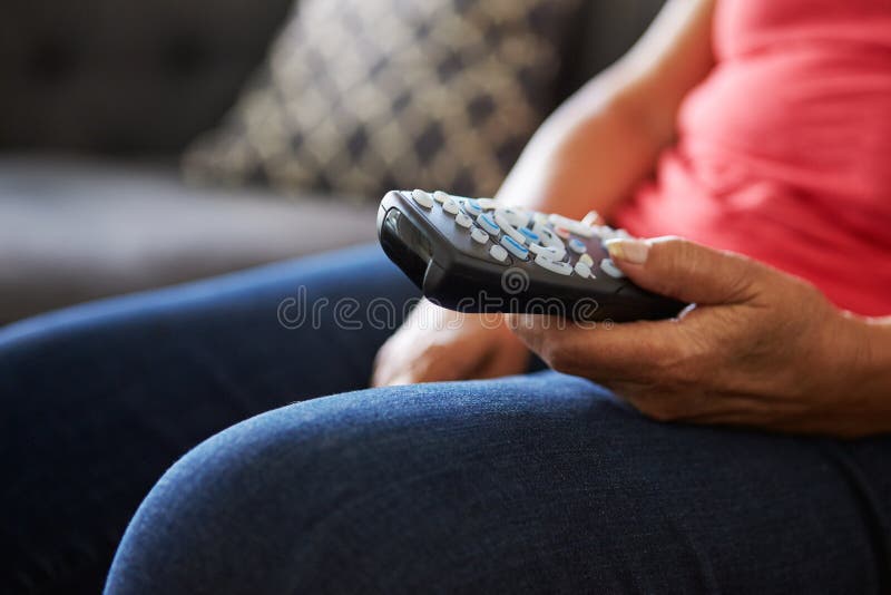 Chiuda su della donna senior che si siede sulla ripresa esterna di Sofa Holding TV fotografia stock Chiuda su della donna senior che si siede sulla ripresa esterna di Sofa Holding TV fotografia stock