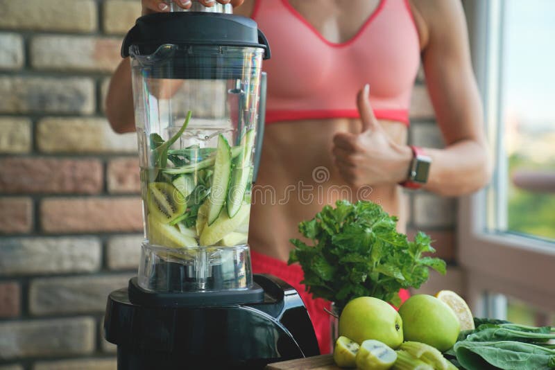 Healthy eating, cooking, vegetarian food, dieting and people concept - close up of young woman with blender and green vegetables making detox shake or smoothie at home. Healthy eating, cooking, vegetarian food, dieting and people concept - close up of young woman with blender and green vegetables making detox shake or smoothie at home