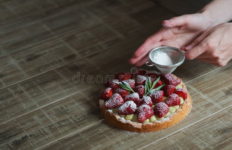 Close up of female pastry chef's hand decorating top of delicious French strawberry cake. Cooking dessert in the kitchen. Close up, selective focus. Close up of female pastry chef's hand decorating top of delicious French strawberry cake. Cooking dessert in the kitchen. Close up, selective focus.