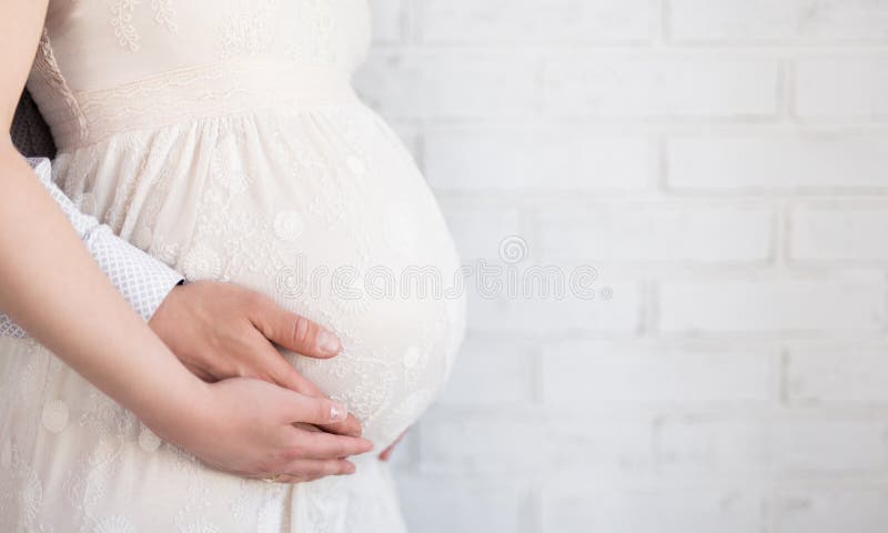Chiuda su della pancia incinta con le mani dei genitori e dello spazio sopra il whi
