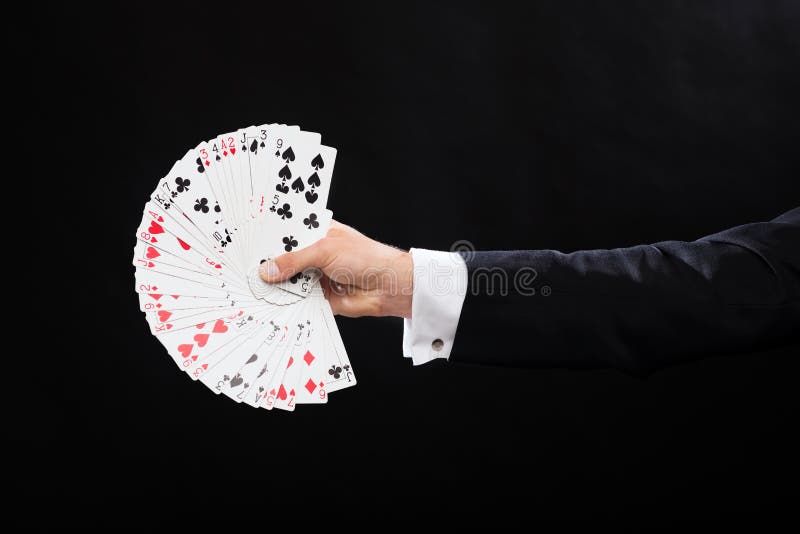 Chiuda su delle carte da gioco della tenuta della mano del mago immagini stock libere da diritti Chiuda su delle carte da gioco della tenuta della mano del mago immagini stock libere da diritti