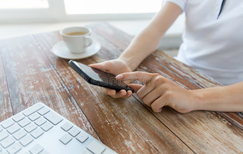 Chiuda su delle mani con lo Smart Phone alla tavola dell'ufficio immagine stock Chiuda su delle mani con lo Smart Phone alla tavola dell'ufficio immagine stock