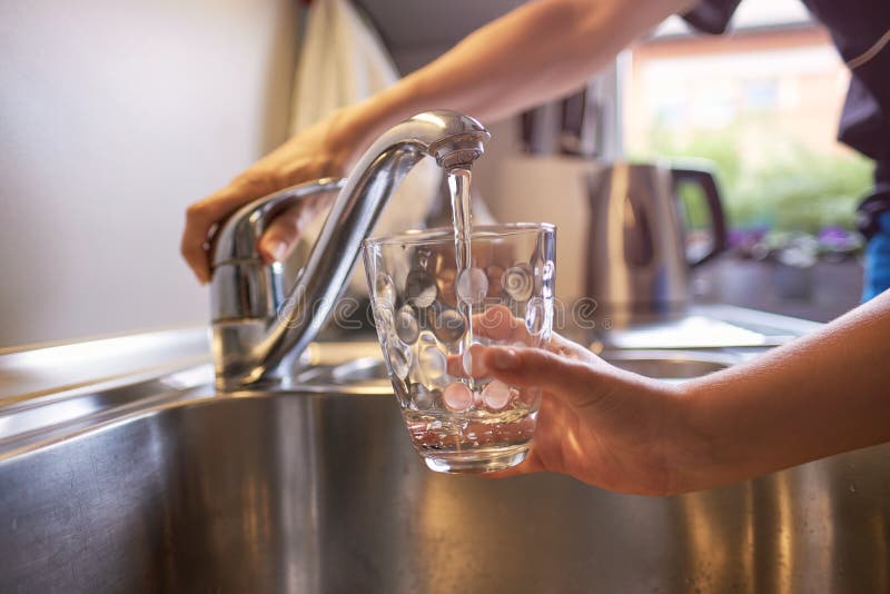 Chiuda su delle mani dei bambini e della donna, versando il vetro di acqua dolce dal rubinetto in cucina fotografie stock Chiuda su delle mani dei bambini e della donna, versando il vetro di acqua dolce dal rubinetto in cucina fotografie stock