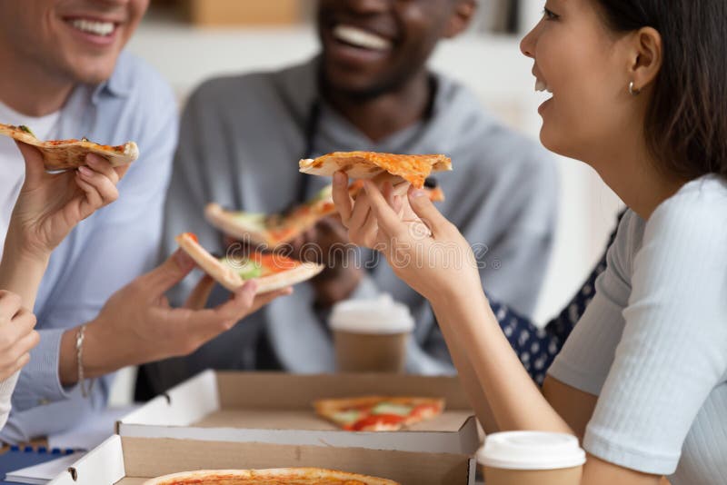 Chiuda su di diversi giovani sorridenti godono della pizza fotografia stock Chiuda su di diversi giovani sorridenti godono della pizza fotografia stock
