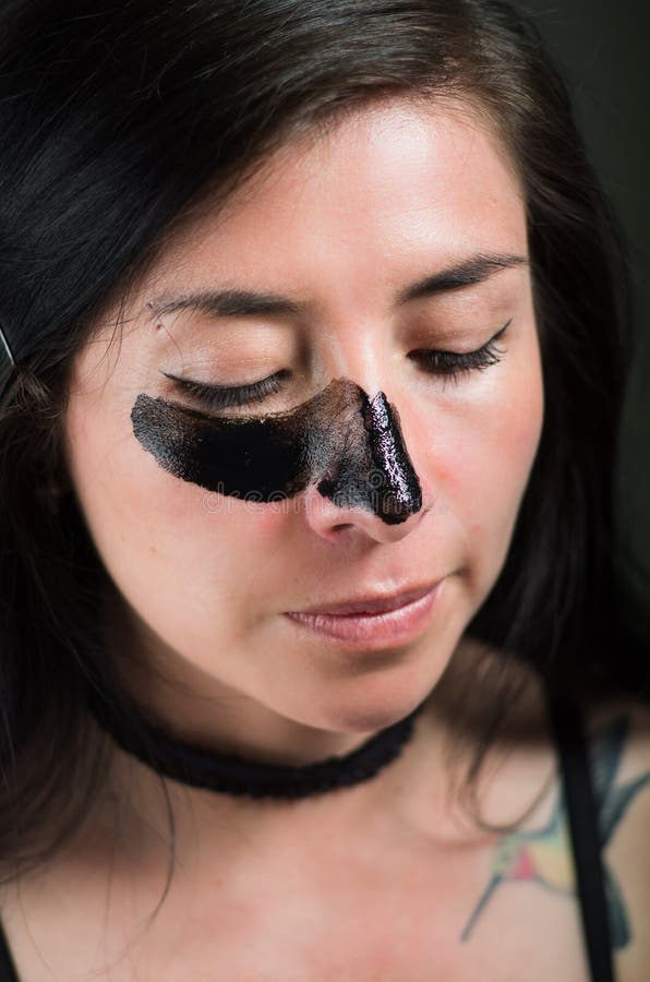 Chiuda su di una giovane donna di bellezza che aplying una maschera nera per pulire la pelle immagini stock Chiuda su di una giovane donna di bellezza che aplying una maschera nera per pulire la pelle immagini stock
