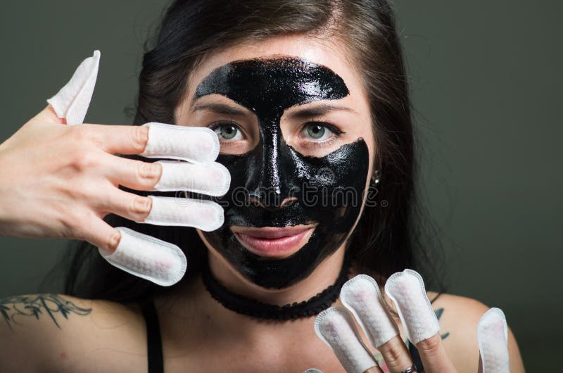 Chiuda su di una giovane donna di bellezza che usando una maschera di protezione nera ed indossando il protettore dei chiodi nei immagini stock Chiuda su di una giovane donna di bellezza che usando una maschera di protezione nera ed indossando il protettore dei chiodi nei immagini stock