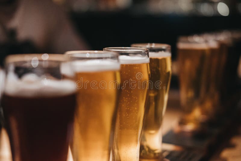 Chiuda su di uno scaffale dei generi differenti di birre, scuri per accendersi, su una tavola fotografia stock libera da diritti