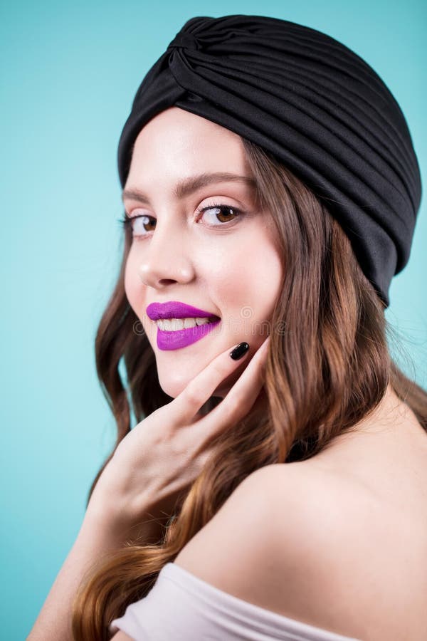 Chiuda sul ritratto della donna castana sorridente felice in un black hat su fondo blu fotografia stock libera da diritti Chiuda sul ritratto della donna castana sorridente felice in un black hat su fondo blu fotografia stock libera da diritti