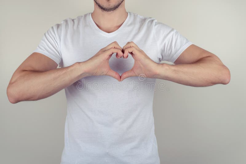 Chiuda sul ritratto della foto del tipo muscolare attraente piacevole sveglio bello che fa il cuore sul petto isolato sulla copia immagine stock libera da diritti Chiuda sul ritratto della foto del tipo muscolare attraente piacevole sveglio bello che fa il cuore sul petto isolato sulla copia immagine stock libera da diritti