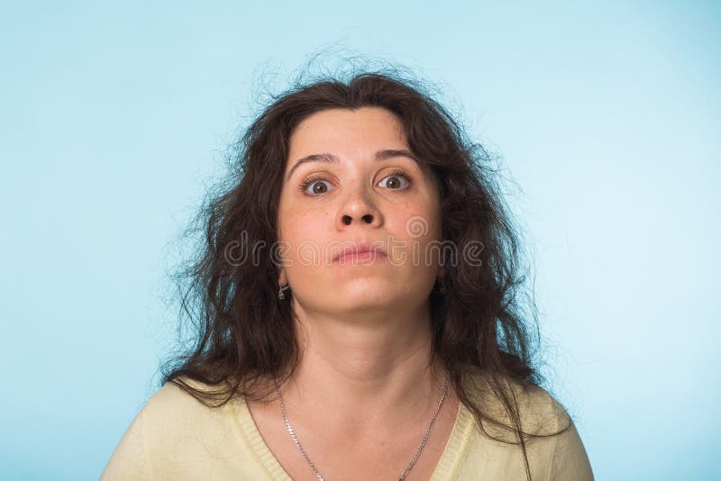 Chiuda sul ritratto di bella giovane donna con capelli ricci su fondo blu fotografia stock Chiuda sul ritratto di bella giovane donna con capelli ricci su fondo blu fotografia stock
